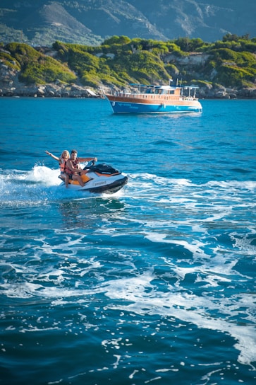 A happy couple riding a bright yellow jet ski on a sunny lake with clear blue skies.