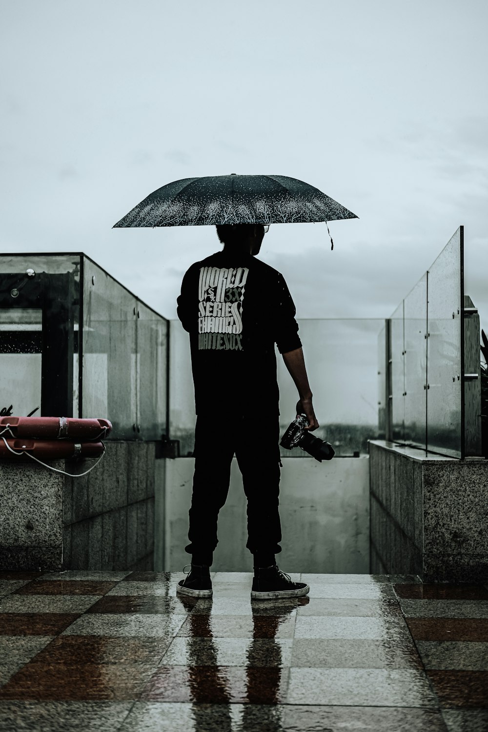a man standing in the rain holding an umbrella