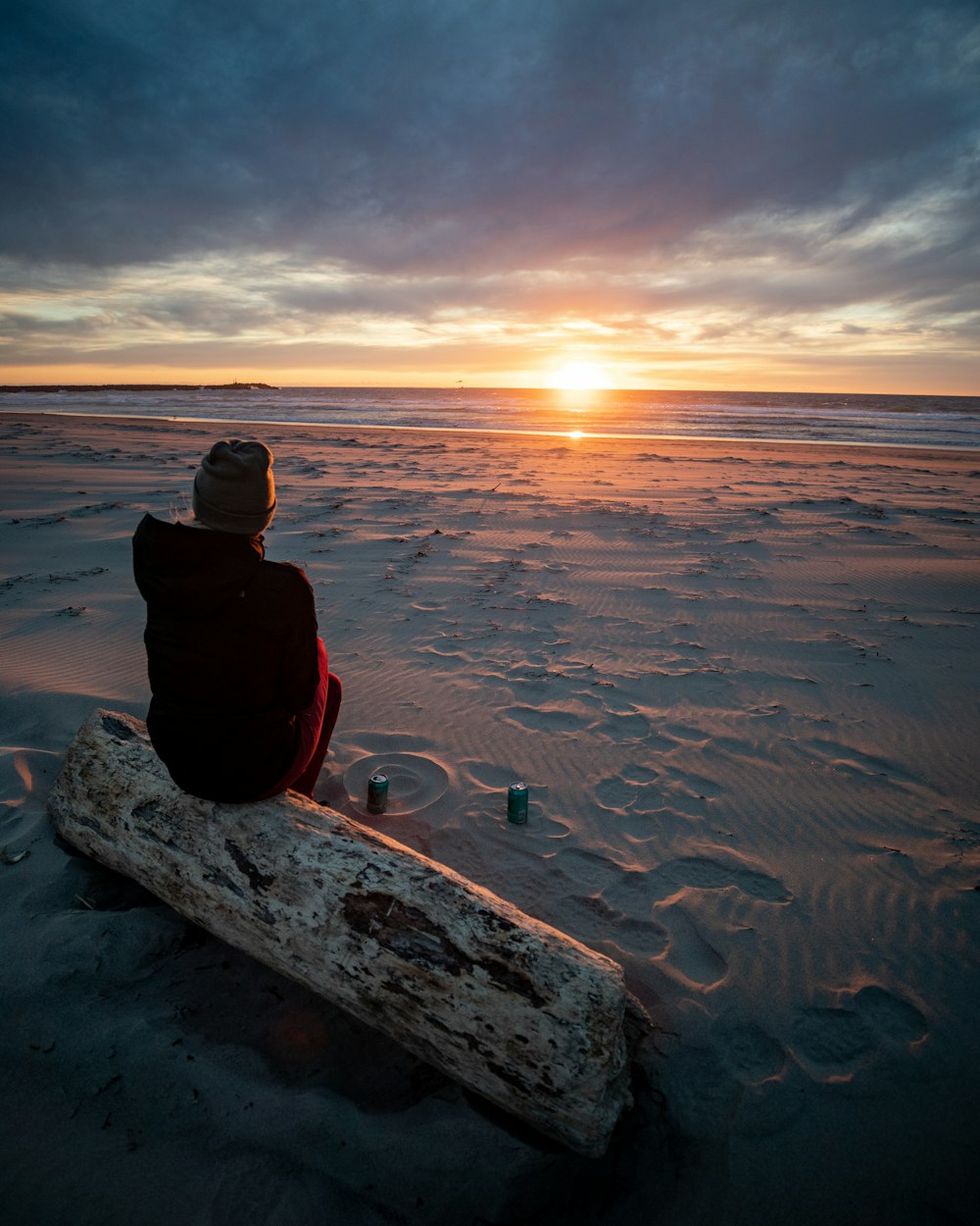 a person sitting on a log in the sand