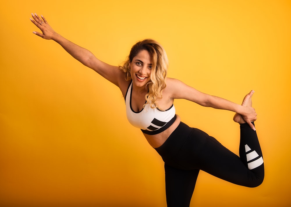 a woman is doing a yoga pose on a yellow background