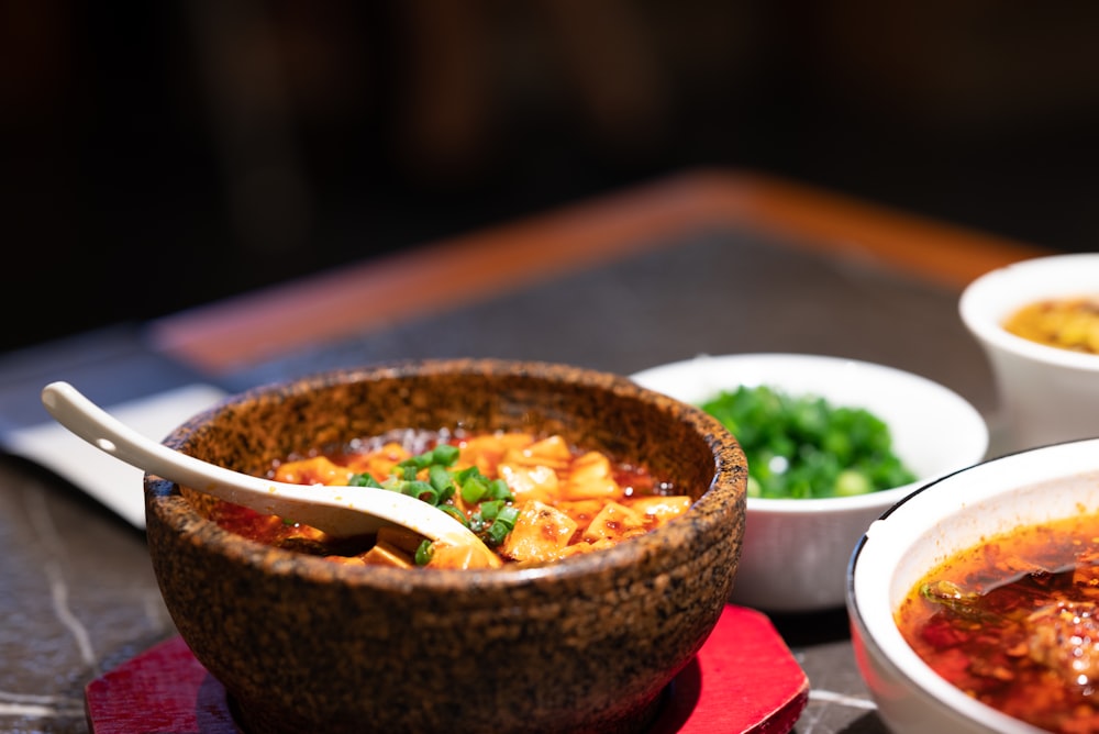 a bowl of soup and two bowls of soup on a table