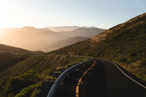 Sunset casting golden light over a winding road through Sikkim’s green hills with our cab in the distance