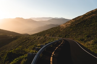 A winding mountain trail bathed in golden sunset light, inviting travelers to explore.