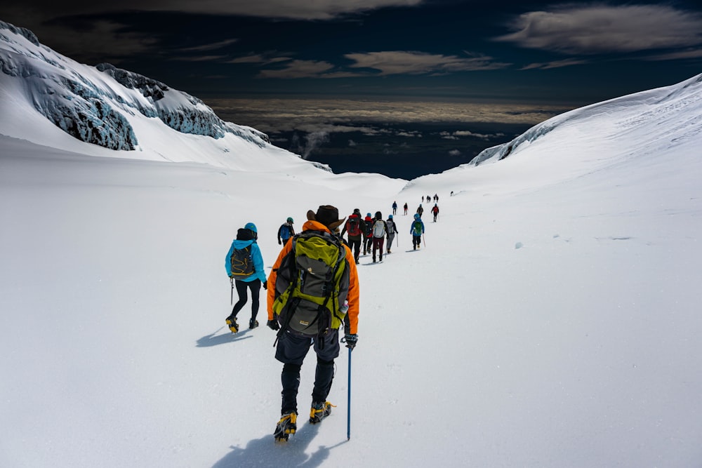 um grupo de pessoas caminhando até uma montanha coberta de neve