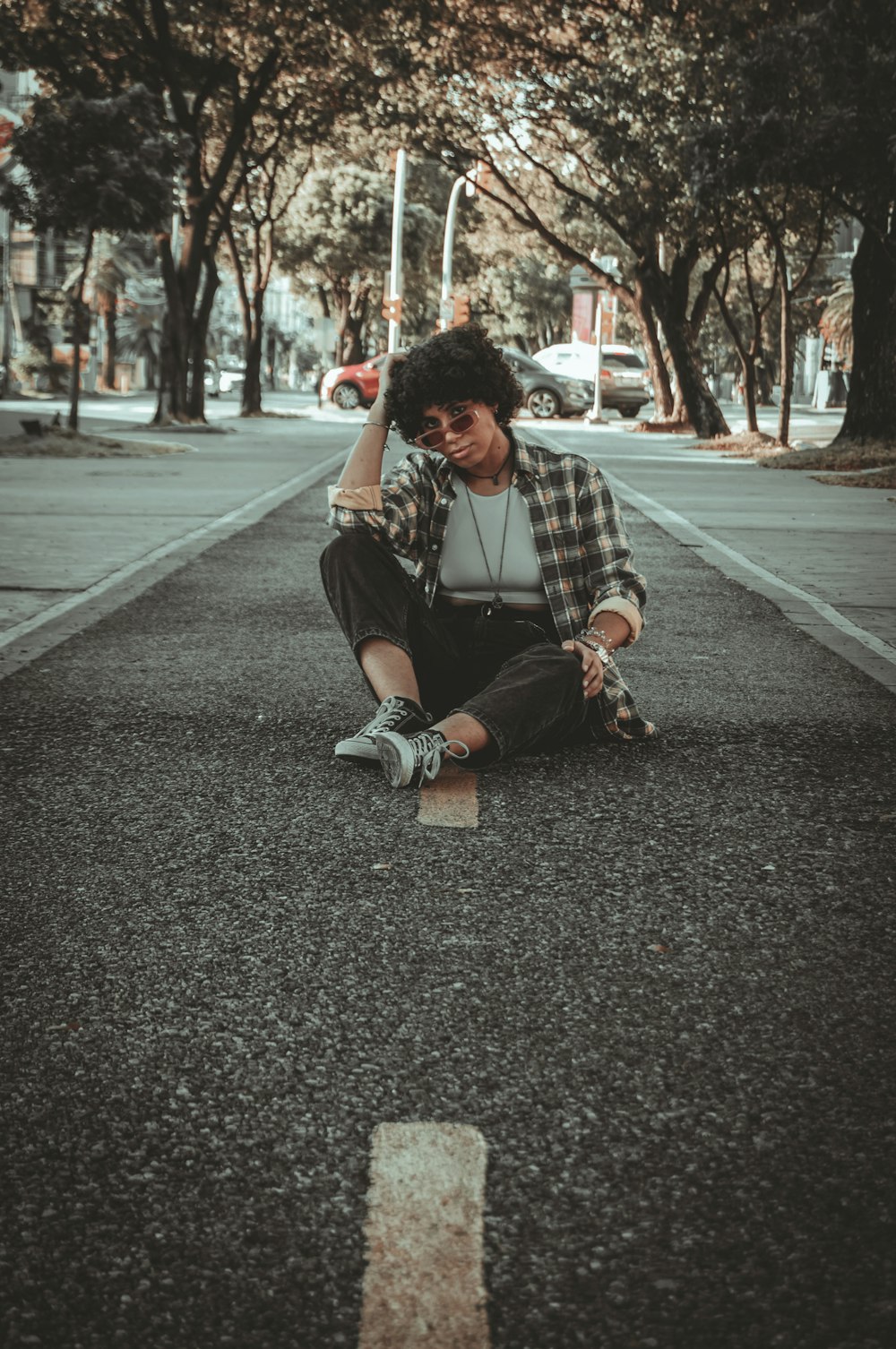 a young man sitting on the side of a road