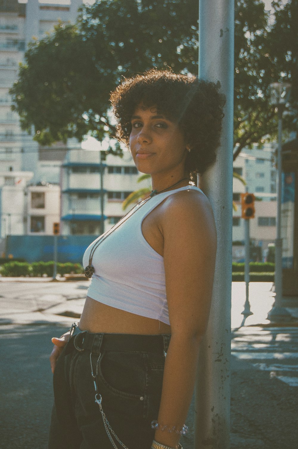 a woman standing next to a pole on a city street