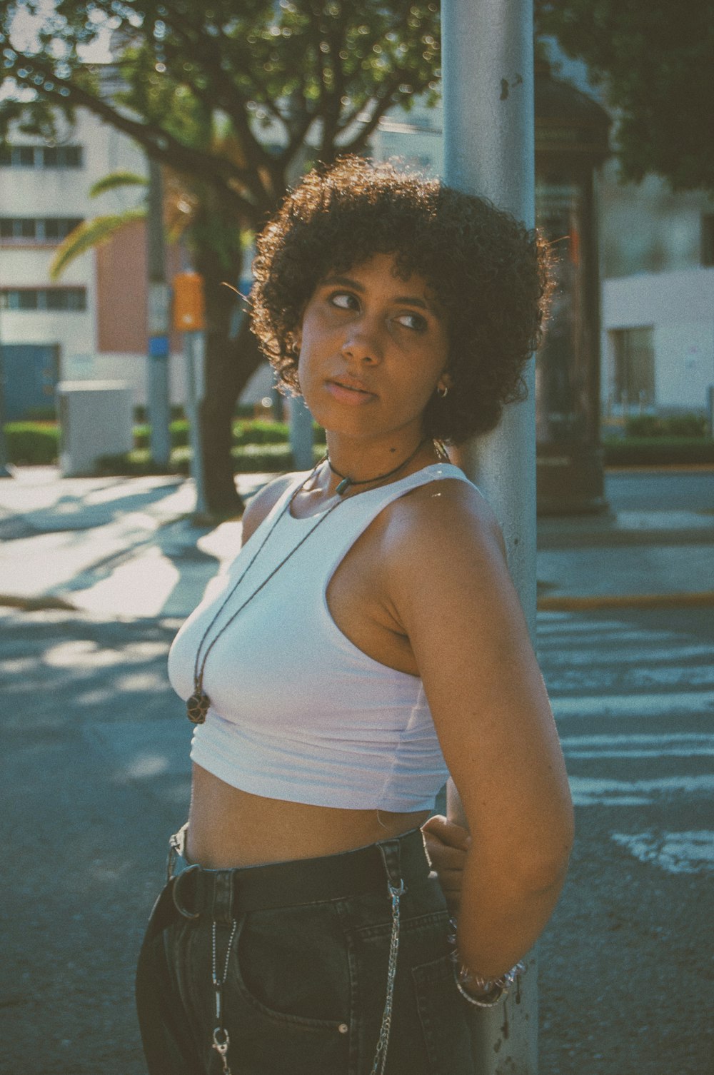 a woman standing next to a pole on a city street