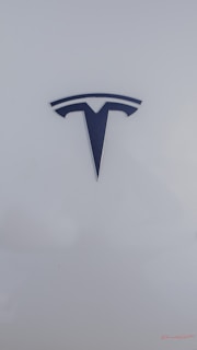 A sleek, metallic logo in the shape of a T sits prominently against a smooth, white background, conveying a sense of modern elegance and sophistication.
