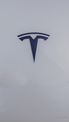 A sleek, metallic logo in the shape of a T sits prominently against a smooth, white background, conveying a sense of modern elegance and sophistication.