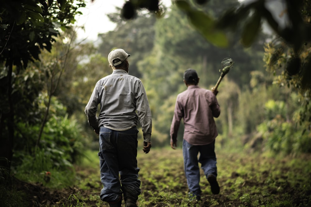 Un par de hombres caminando por un camino de tierra