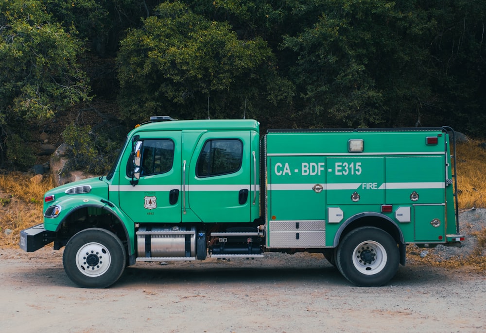 a green fire truck parked on a dirt road