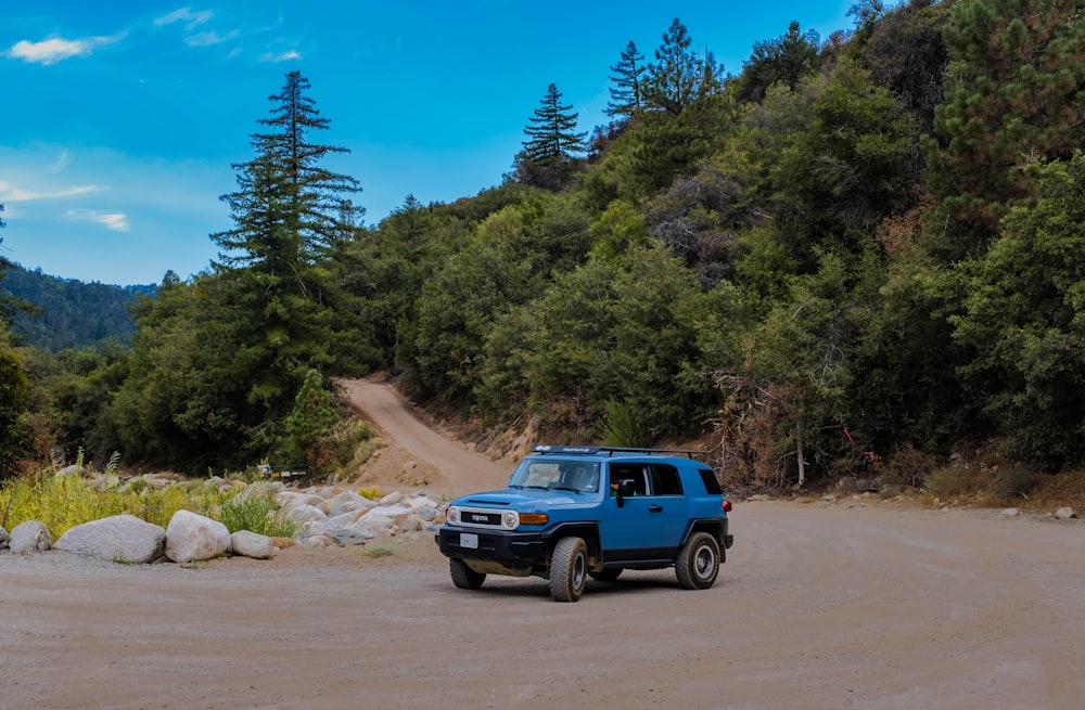 a blue pick up truck driving down a dirt road