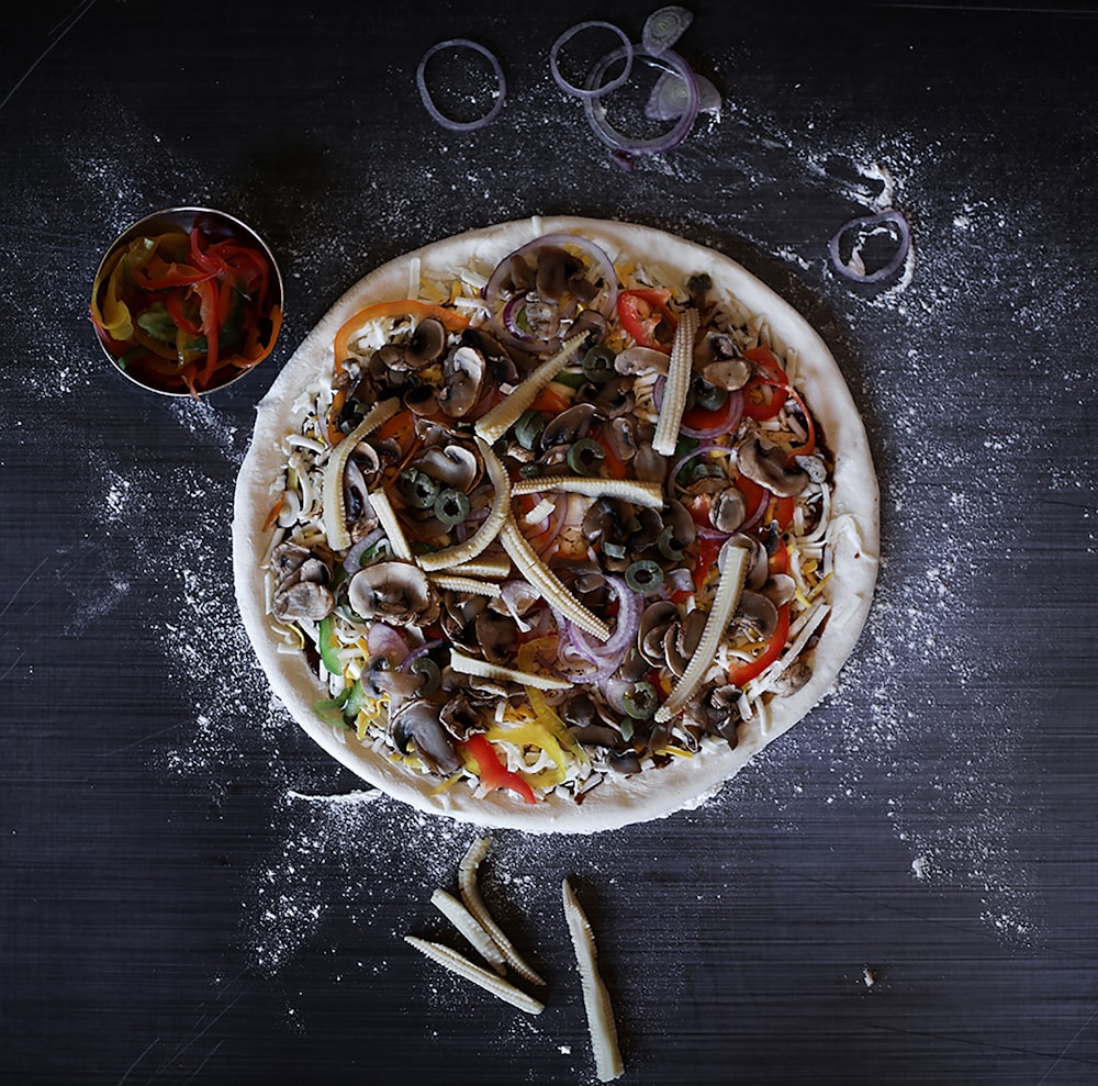 Una pizza sentada encima de una mesa cubierta de ingredientes