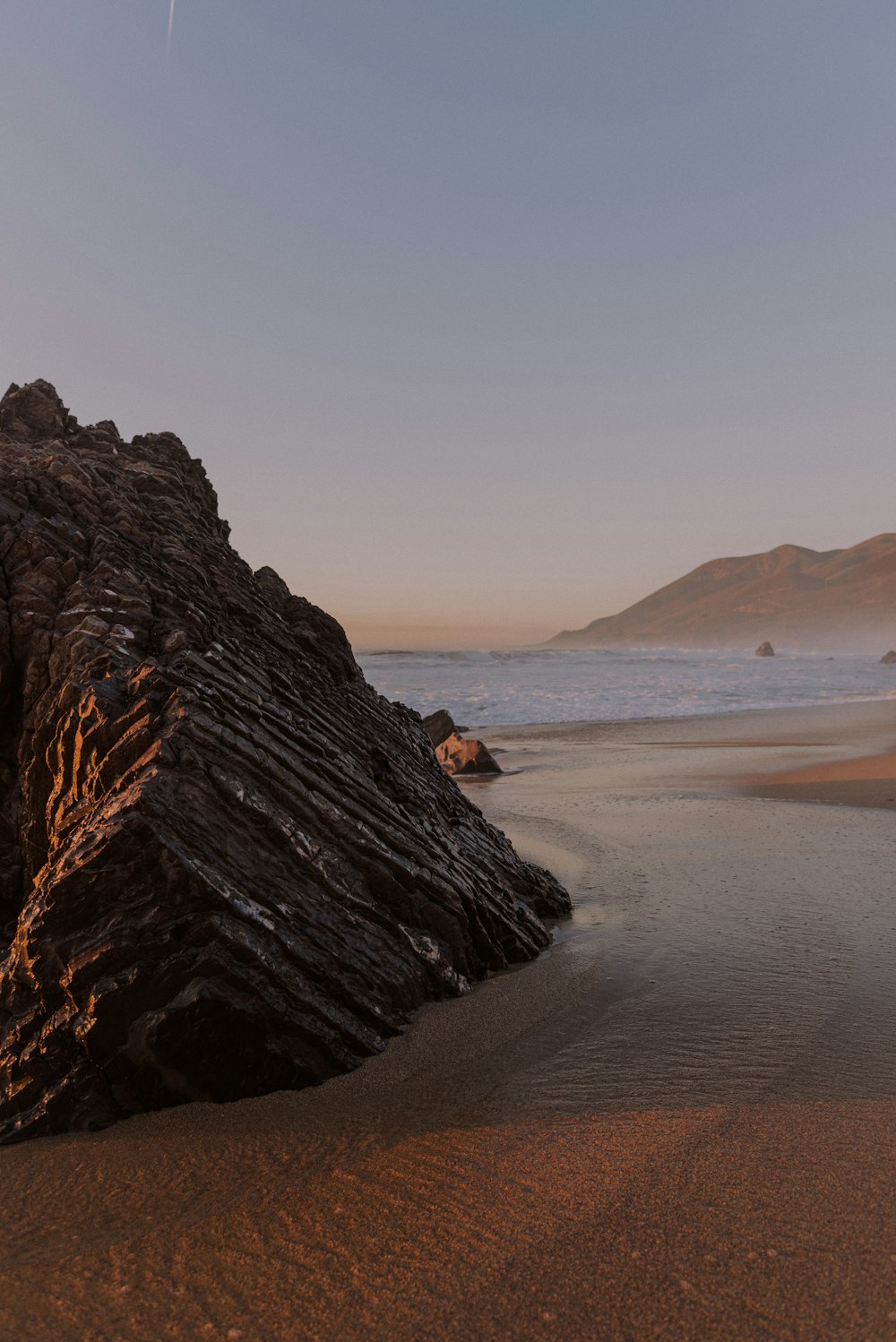 a large rock sitting on top of a sandy beach