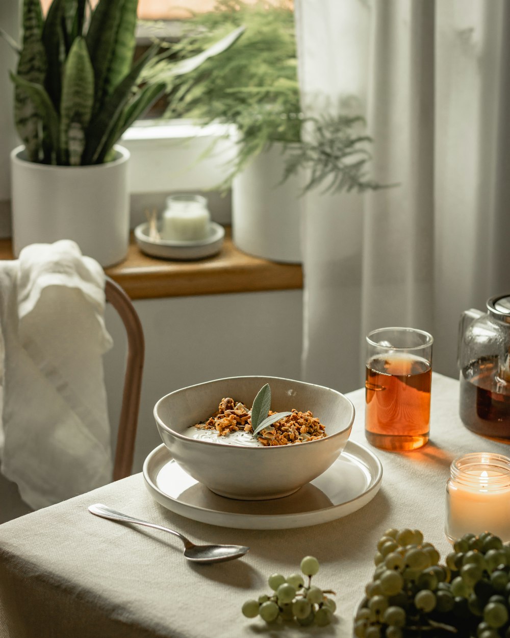 a bowl of cereal on a table next to a glass of tea