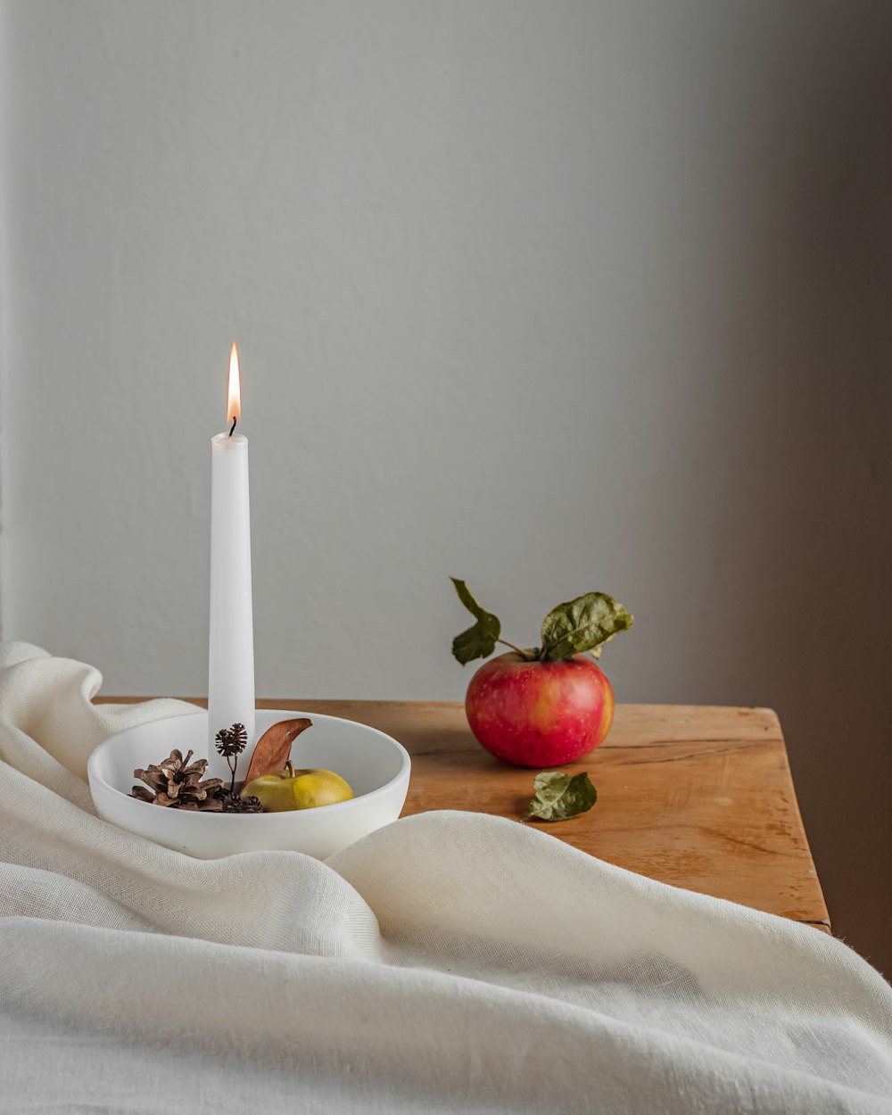 uma vela branca sentada em cima de uma mesa de madeira