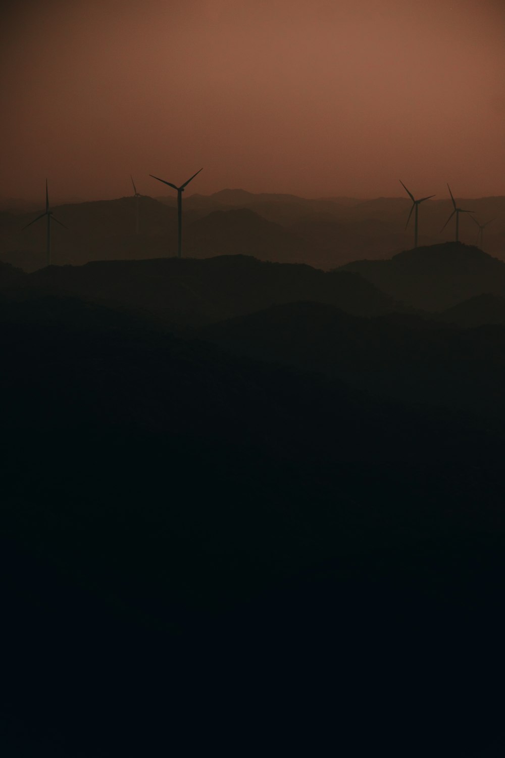 Un grupo de molinos de viento en una colina al atardecer