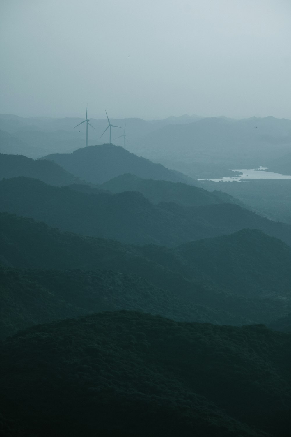 a wind farm on a foggy day in the mountains