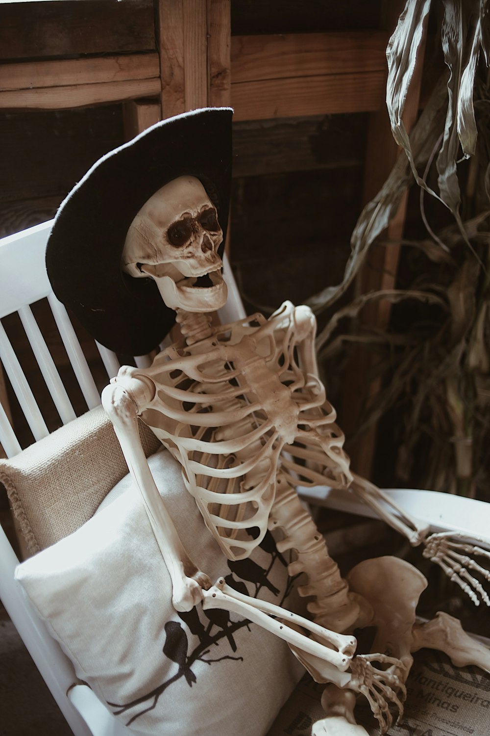 a skeleton sitting in a chair with a hat on