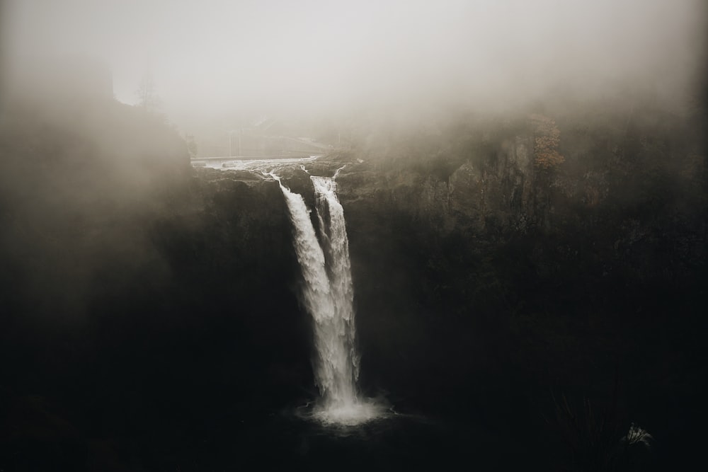 a waterfall in the middle of a foggy forest