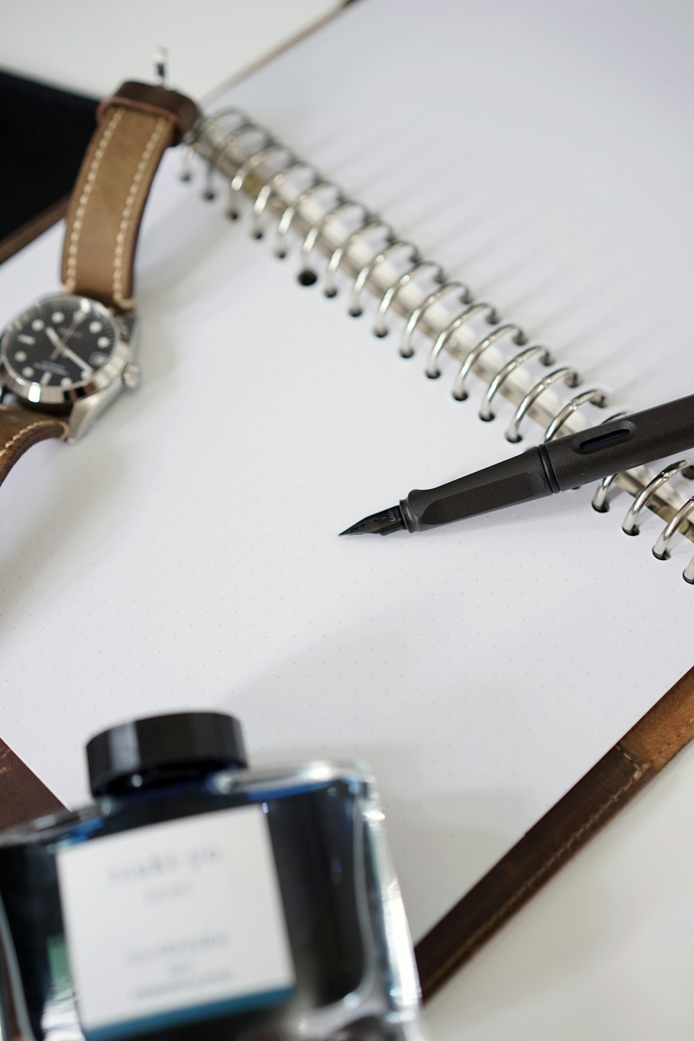 a notepad with a pen and a watch on it