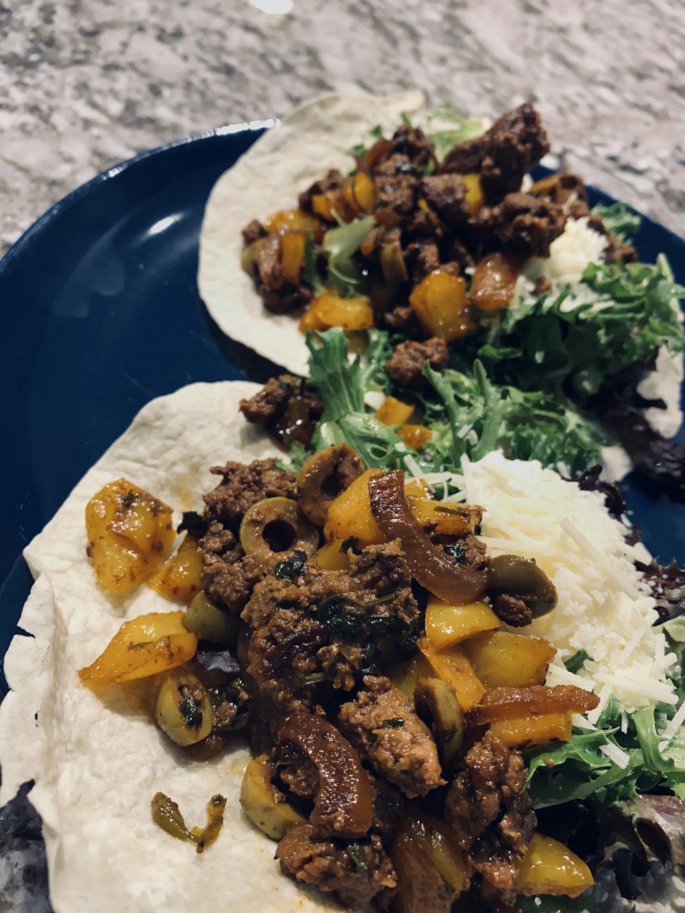 two tacos with meat and vegetables on a blue plate