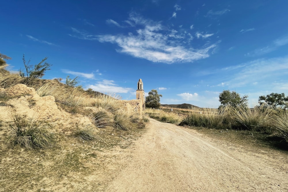 a dirt road with a tower in the distance