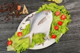 a white plate topped with a fish and lettuce