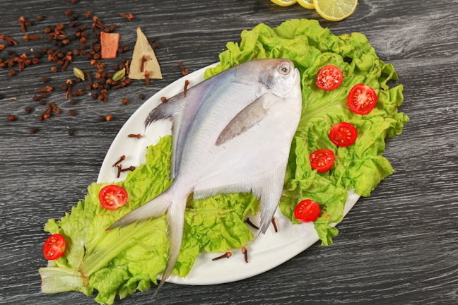 a white plate topped with a fish and lettuce