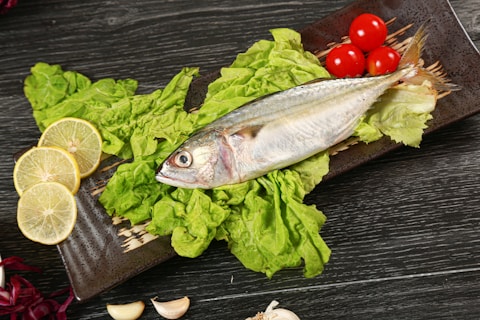 a fish is sitting on some lettuce and tomatoes