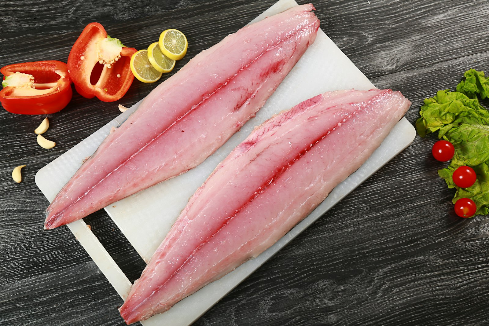 To ferske fiskefileter på skjærefjøl, klare til å porsjoneres når du skal regne ut hvor mye fisk per person