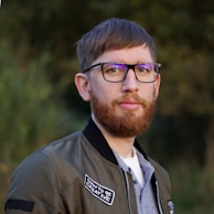 a man with a beard wearing glasses and a jacket