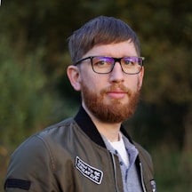 a man with a beard wearing glasses and a jacket