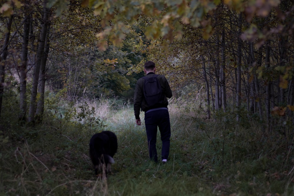 a man walking through a forest with a dog