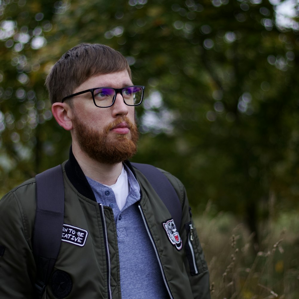 a man with a beard and glasses standing in a field