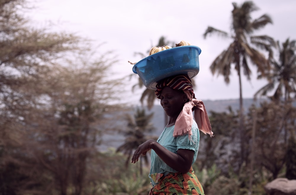 a woman carrying a blue bowl on her head