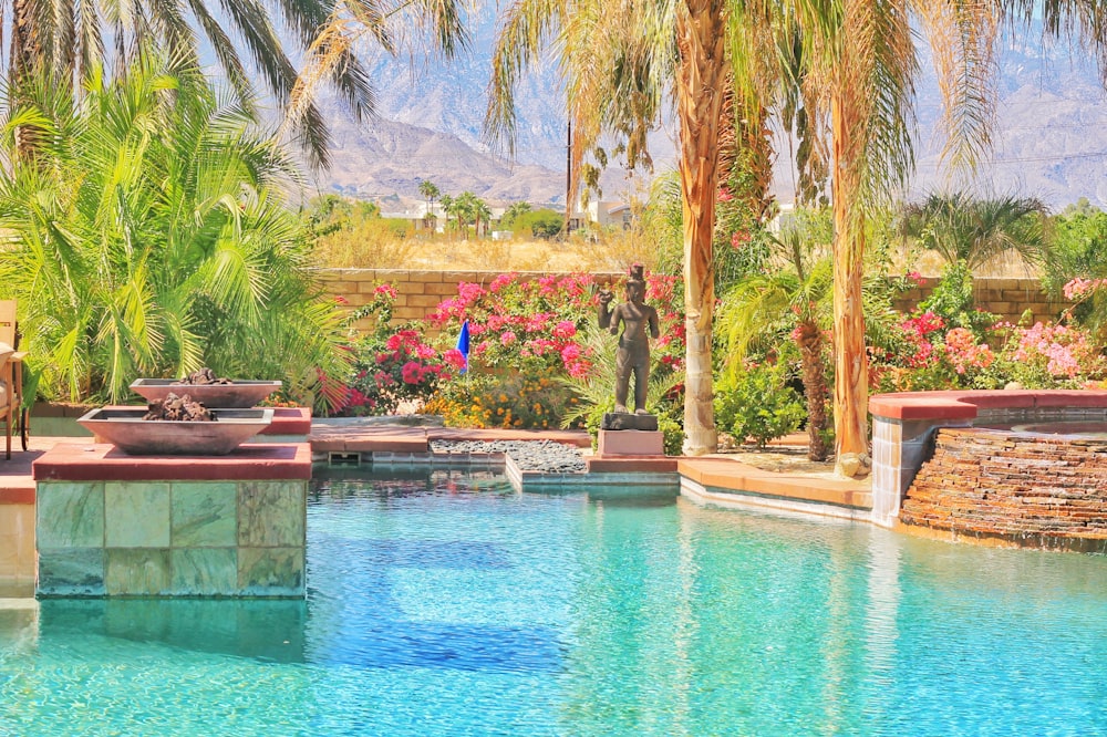 a pool surrounded by palm trees and flowers