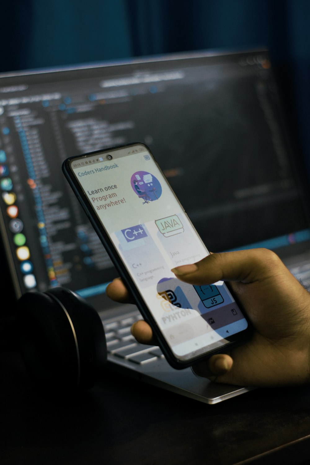 a person holding a cell phone in front of a laptop