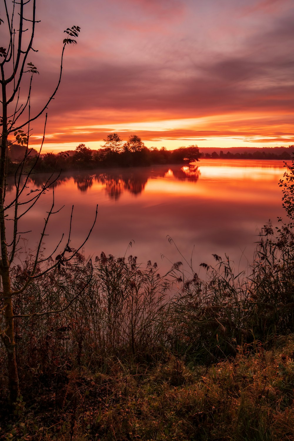 the sun is setting over a calm lake