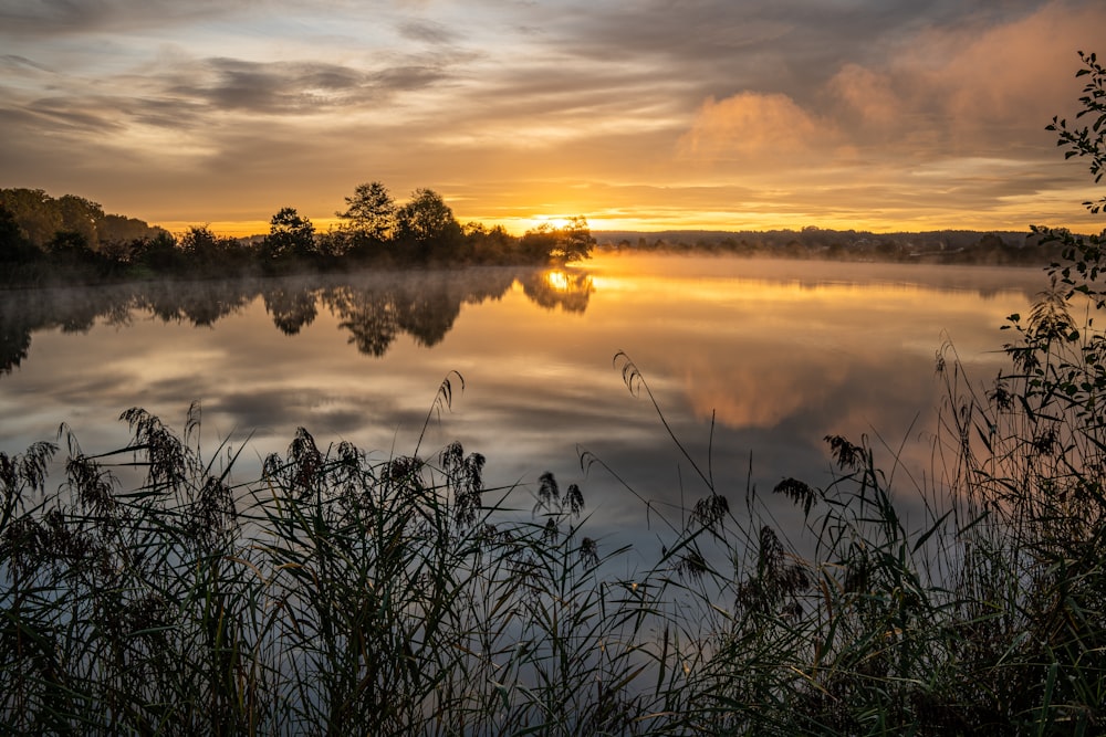 the sun is setting over a calm lake