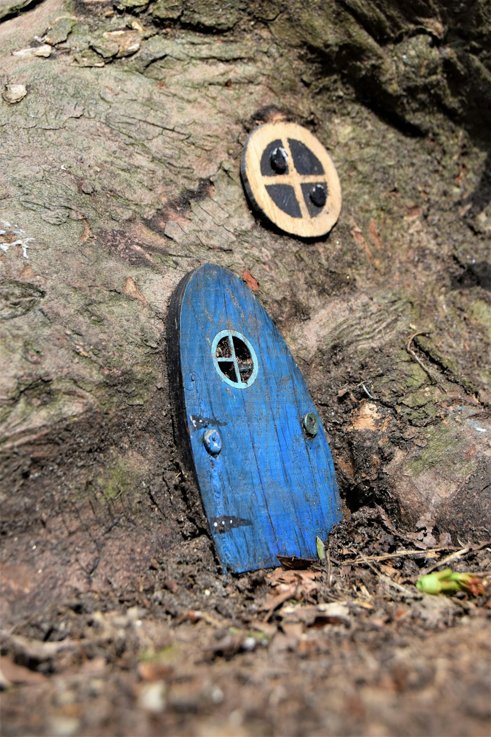 a blue hobbot sitting on the ground next to a tree