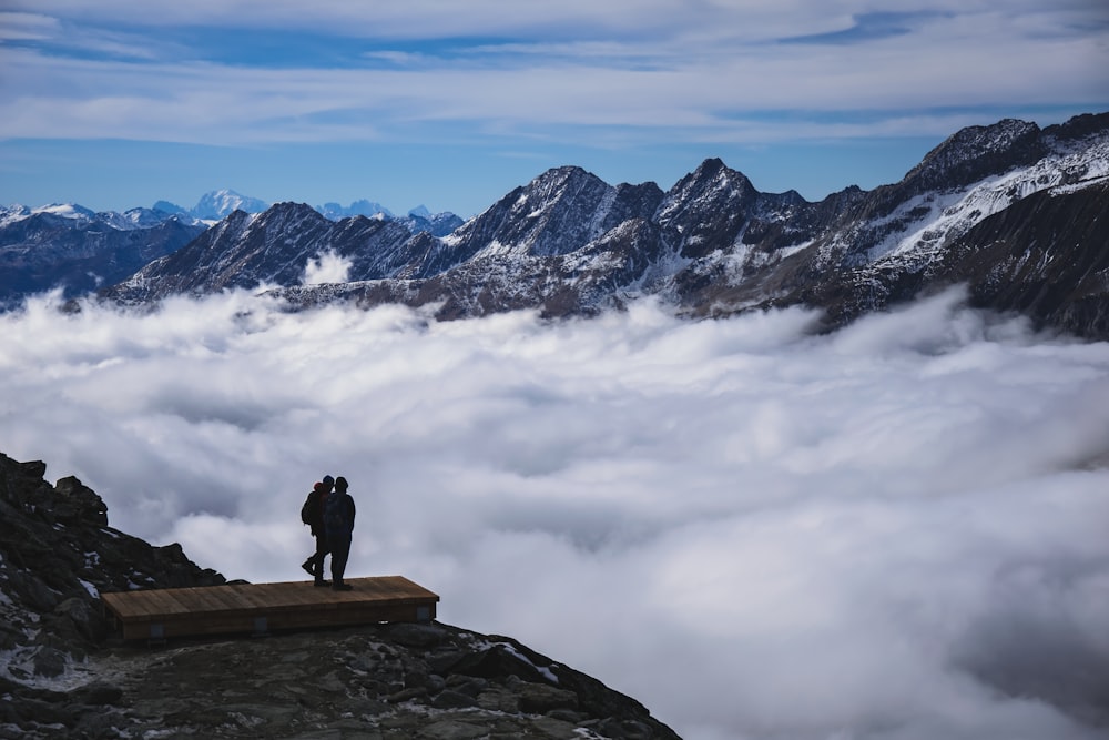 um homem de pé no topo de uma montanha cercada por nuvens