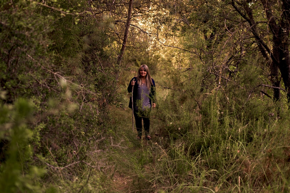 a woman is walking through the woods with a backpack