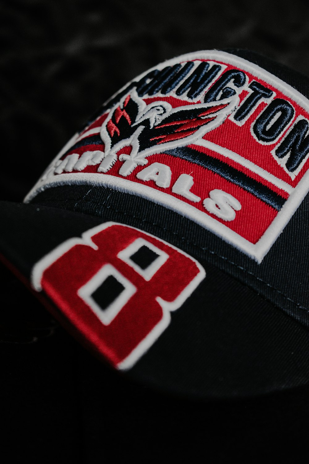 una gorra de béisbol negra y roja con un logotipo rojo y blanco
