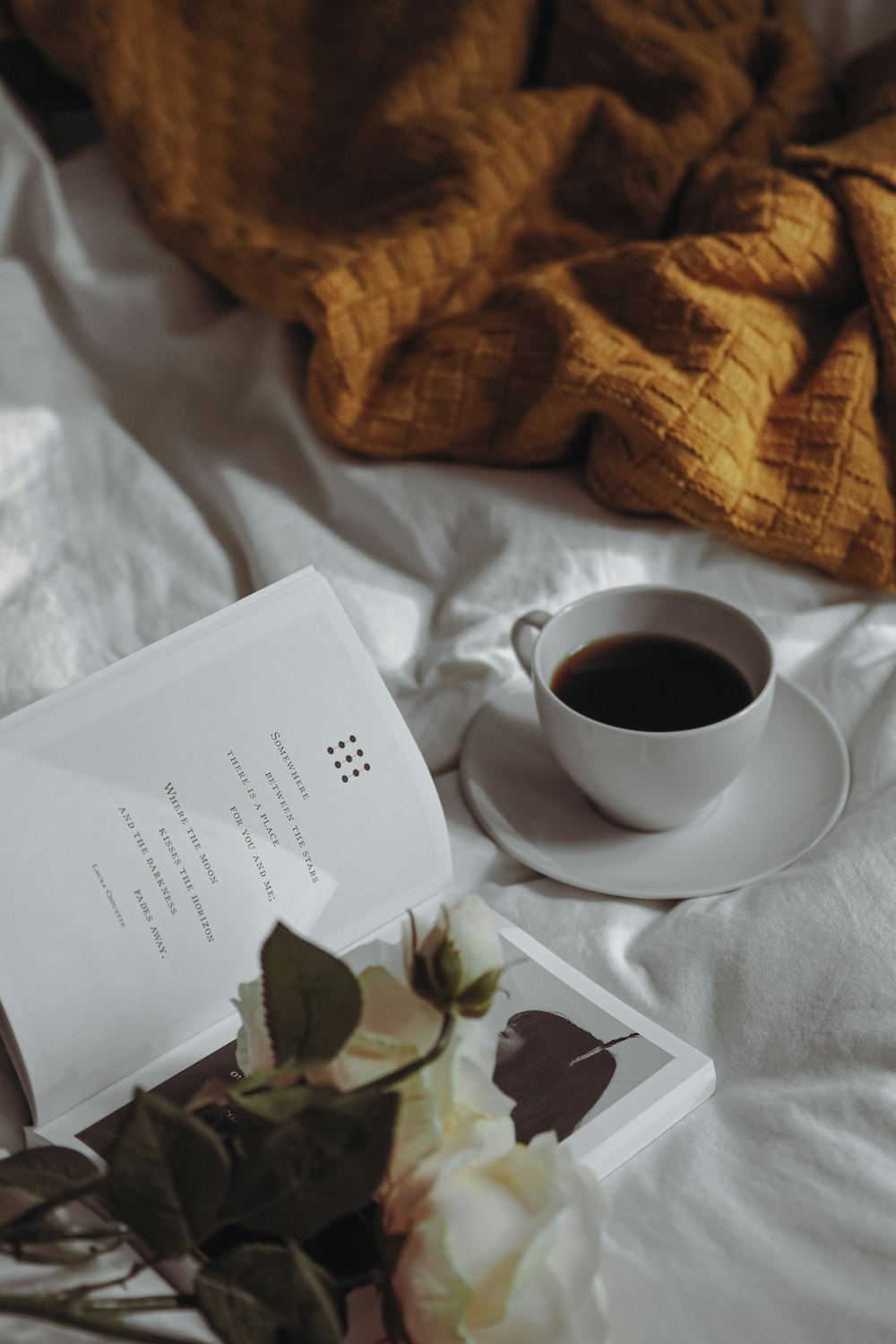 a cup of coffee and a book on a bed