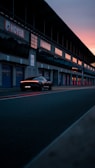 A sleek sports car parked on a racetrack at sunset.