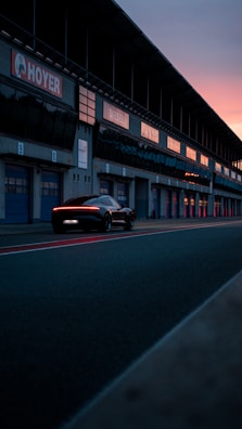 A sleek sports car parked on a racetrack at sunset.
