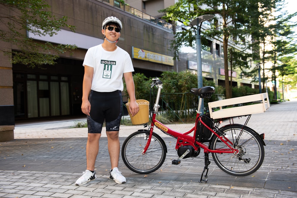 a man standing next to a red bike