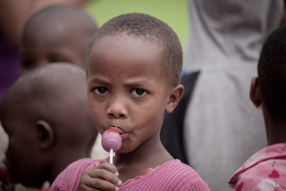 a young child is chewing on a lollipop