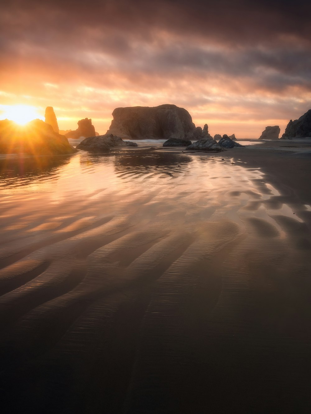 the sun is setting over the ocean and rocks